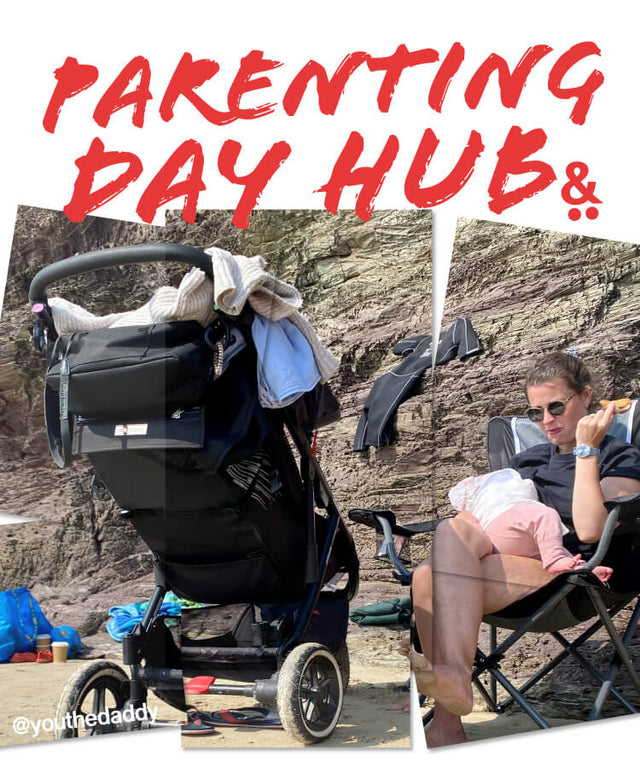 Mum sitting on a chair at the beach feeding baby with a 3 wheel pram in the foreground - parenting day hub -  philandteds.com